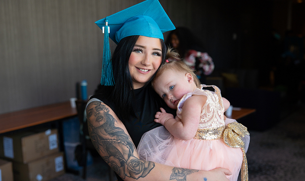 MaKami College graduate holding a child